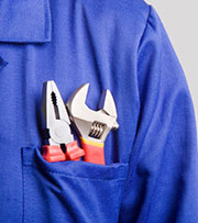 A pair of pliers and an adjustable crescent wrench sitting in the front pocket of a polo shirt